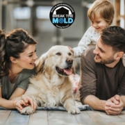 A happy family laying on the kitchen floor with their dog